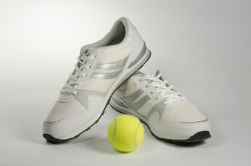 White men's sneakers and a tennis ball