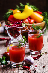Spicy tomato juice with salt and spices, vintage wooden backgrou