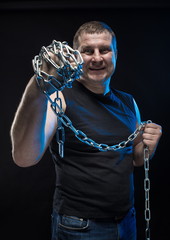 Actor Brutal man with a chain in his hands on a black background.