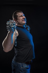 Actor Brutal man with a chain in his hands on a black background.
