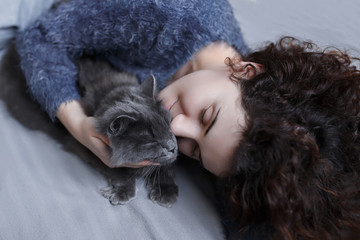 Cute curly girl hugging a fluffy gray cat