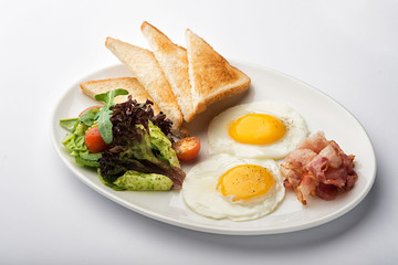 Fried eggs with toast and bacon.