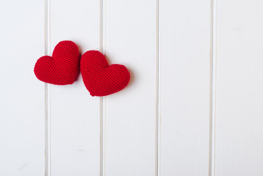 Two knitted hearts on white wooden background. Valentines day cards.