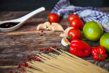 talian food background, with tomatoes, basil, spaghetti, mushrooms, parmesan, olive oil, sauce, lime, garlic, peppercorns, rosemary, thyme. Wooden background with fork