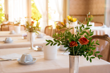 Fototapeta na wymiar Flowers with leaves in vase. Food joint interior. Varied menu and fast service.