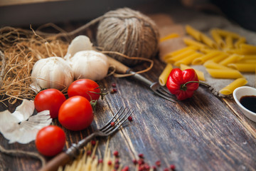 talian food background, with tomatoes, basil, spaghetti, mushrooms, parmesan, olive oil, sauce, lime, garlic, peppercorns, rosemary, thyme. Wooden background with fork