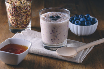 Blueberry milk smoothie, muesli, honey and fresh picked blueberries on wooden background, breakfast on the table
