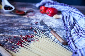 Italian food background, with tomatoes, basil, spaghetti, mushrooms, parmesan, olive oil, sauce, lime, garlic, peppercorns, rosemary, thyme. Wooden background with fork