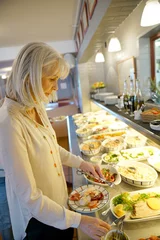  Senior woman in restaurant helping herself at delicatessen buffet © goodluz