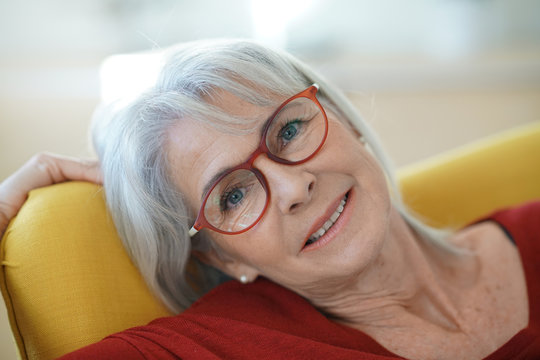 Senior Woman With Red Sweater Relaxing In Armchair