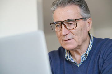 Senior man with eyeglasses reading newspaper