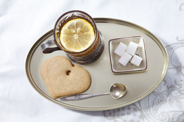 Glass of tea in the cup holder,  saucer with a lemon on a white