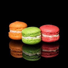 Multicolored macaroons isolated on black background with reflection. Free space for text