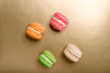 Sweet and colourful macaroons on golden background. Traditional french dessert. Copy space.