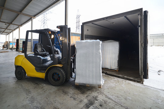 Forklift in warehouse loading box into a car outdoors