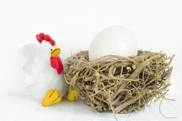 White stuffed chicken and wooden nest with big, huge egg inside in isolated white background.