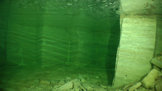 Smooth walls with traces of the cutting blade in a flooded mine for the extraction of building stone.

