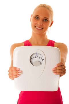 Fit blonde woman holding scale gesturing healthy lifestyle and w