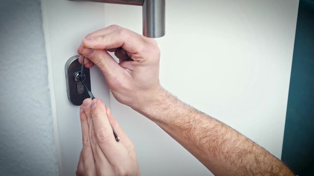 Intruder or Burglar with lockpick tool opens the front door to enter the house. could also be used for key service or locksmith concept