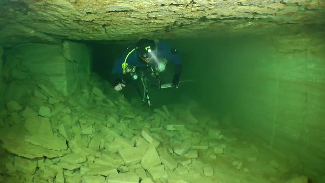 Speleologist swims up to the bifurcation of the corridor of flooded mine.

