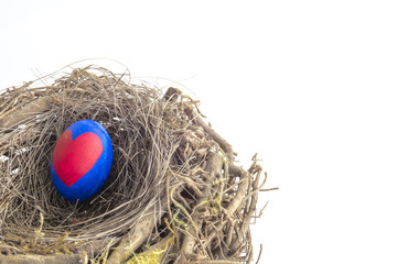Detail of painted Easter egg with a red heart placed in a nest in white isolated background.