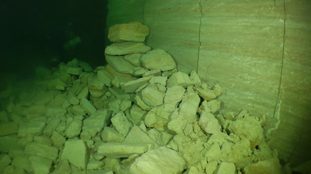 The camera moves along the tunnel of flooded mine and approaching the speleologist who performs any work.

