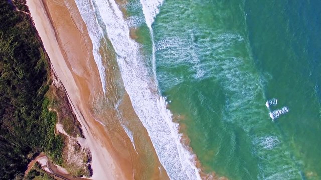 Aerial drone view of beautiful waves coming to sand beach
