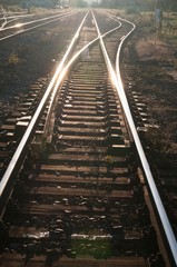 Railway tracks with girder and gravel against sunshine. Vertical photo