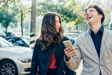Young beautiful couple in love using smart phone together outdoor in the city - interaction, love, technology concept