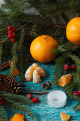 Fototapeta na wymiar Still life of spruce branches, tangerine, pine cones, pine nuts. Blue textured background.