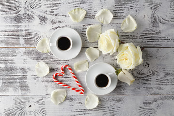 Couple white cups with decoration by red hearts on wooden table.