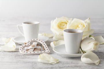 Obraz na płótnie Canvas White roses and two white cups