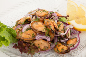 Salad with mussels and onion on a glass plate with lemon