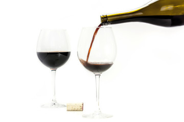 Red wine poured from bottle into glass, on white
