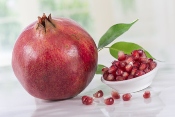 Juicy pomegranate with leaves and garnet grains in a bowl 