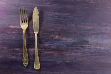 Vintage fork and knife on purple with copyspace