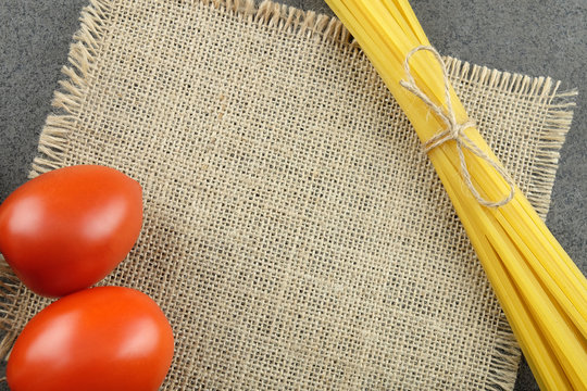 Bavette and tomatoes on a burlap cloth with a dark background with space for the recipe.