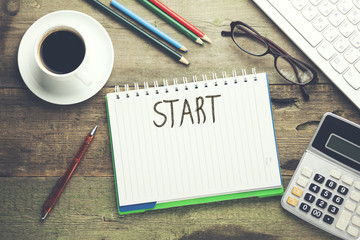 Start  text on notebook with coffee and keyboard on table