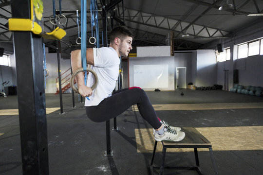 Man doing gym exercise on rings in gym