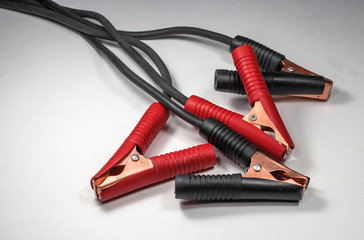 Cables for batteries with the positive and negative terminals on a light background.