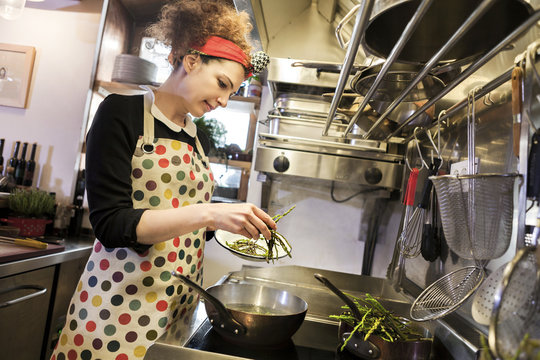 Female chef preparing food in frying pan