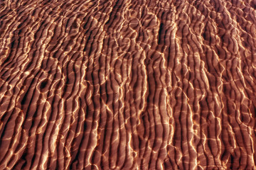 The brown background image of sand and sea with reflect sunlight.By adjustments color balance.