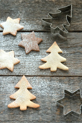 Cookies and molds in the form of Christmas trees and stars on a wooden background.
