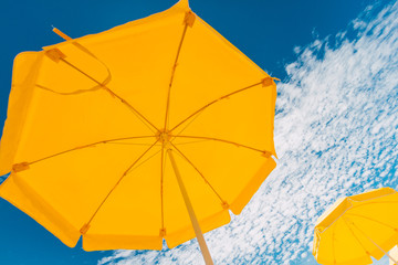 Two yellow umbrellas on the beach against blue sky with clouds i © simonmayer