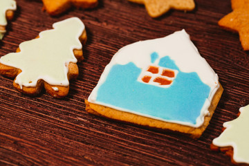 Fototapeta na wymiar gingerbread cookies shaped like a house and firs on dark wooden background