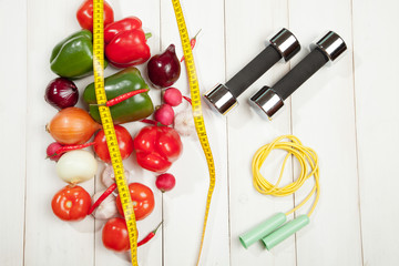 Naklejka na ściany i meble Sport and diet. Healthy lifestyle. Vegetables, dumbbells. Peppers, tomatoes, garlic, onions radishes on a white background