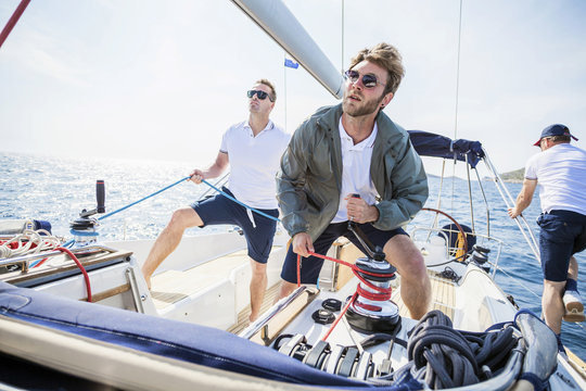 Two men turning cable winch on sail ship