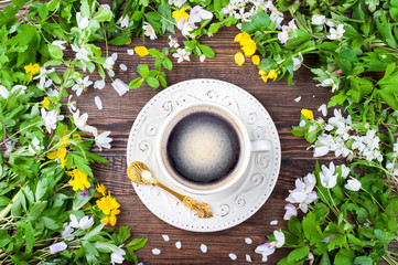 Coffee cup and spring flowers on rustic wooden background. Springtime. Top view