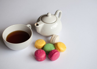 Cup of tea with french macaroon on white  background. Tea pot, cup of tea, color macaroon lying on white
