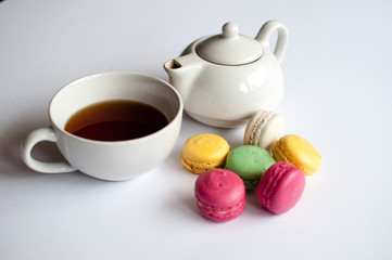 Obraz na płótnie Canvas Cup of tea with french macaroon on white background. Tea pot, cup of tea, color macaroon lying on white